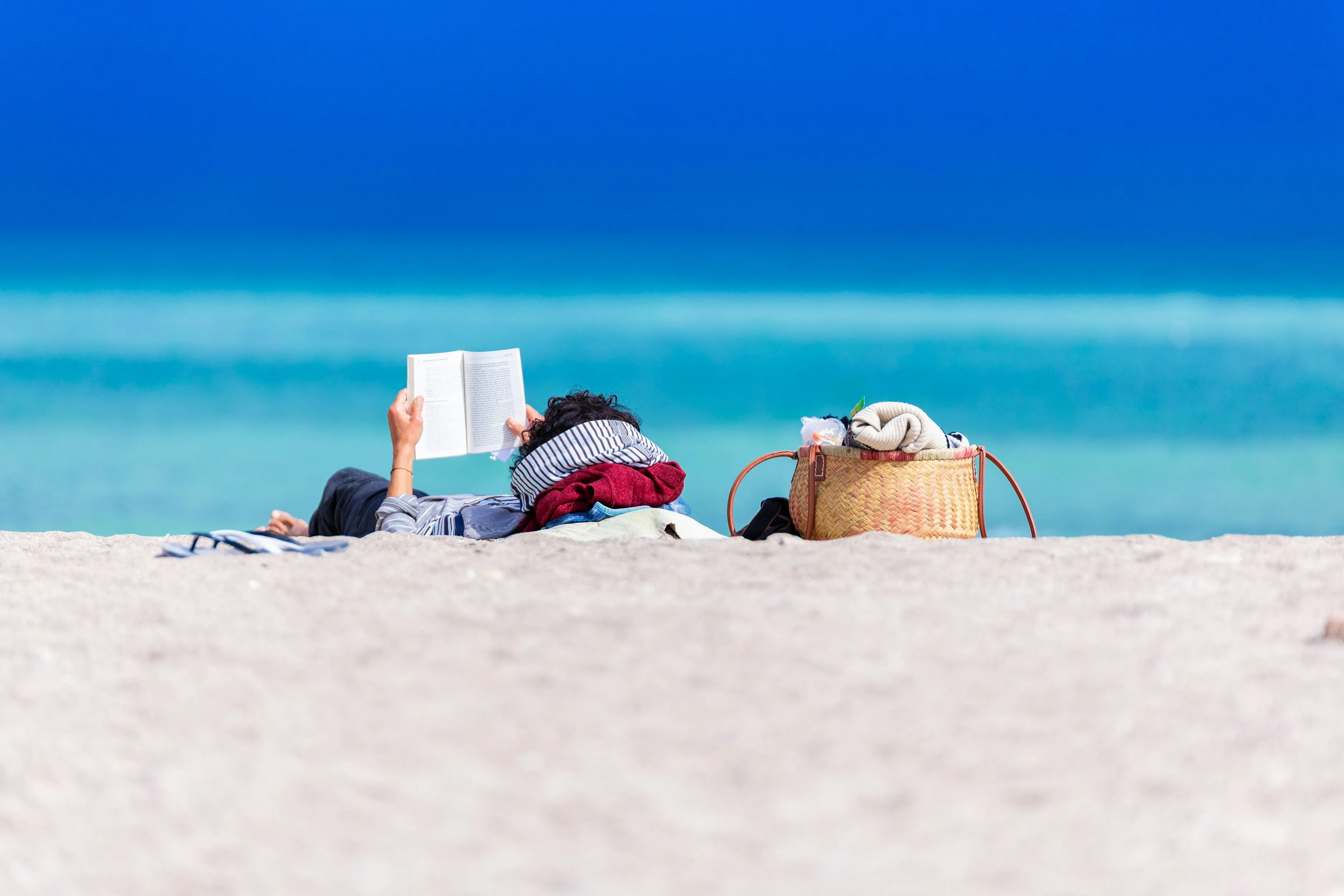 a person lying on a beach reading a book