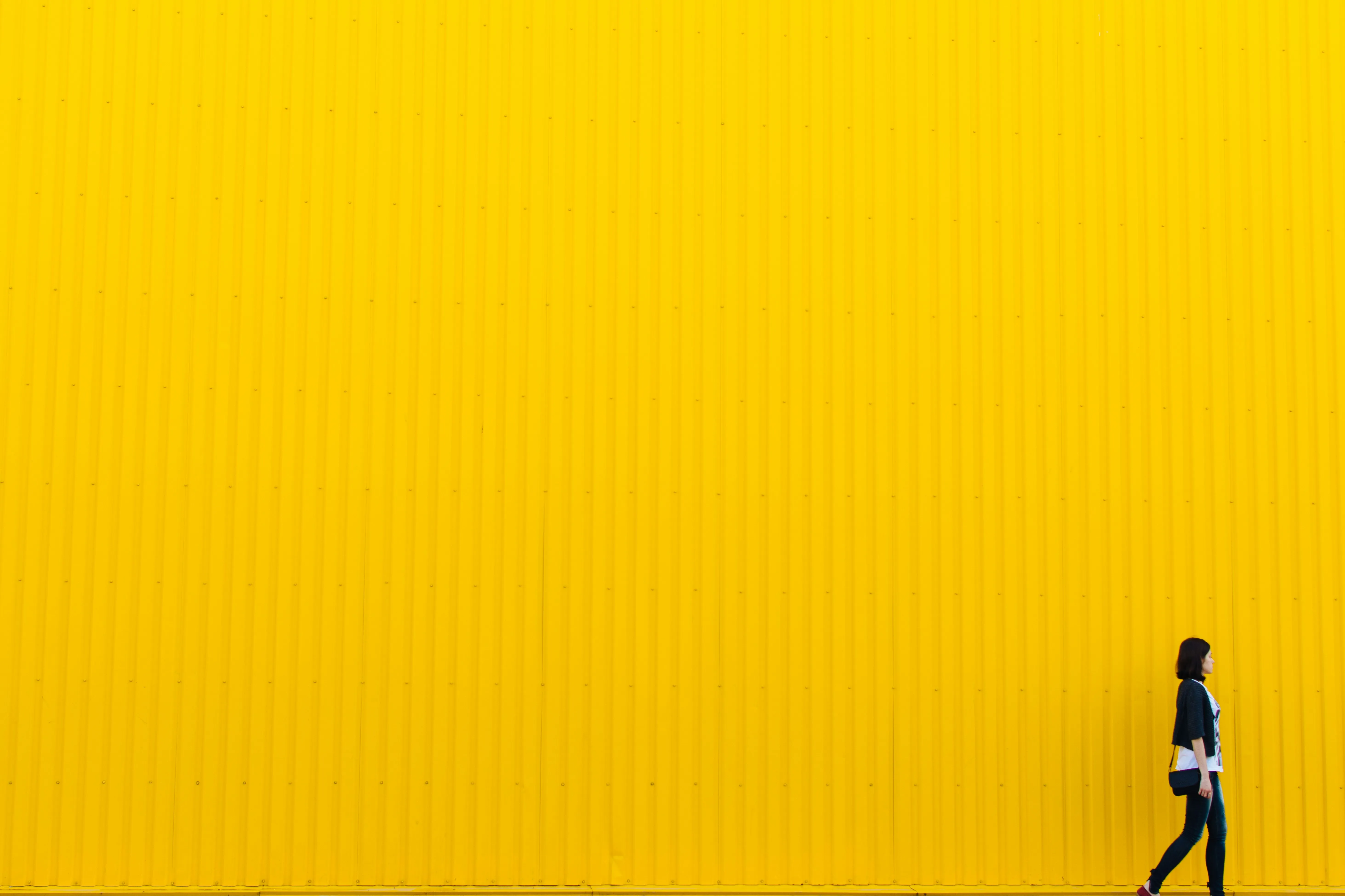 a woman walking past a large yellow poster